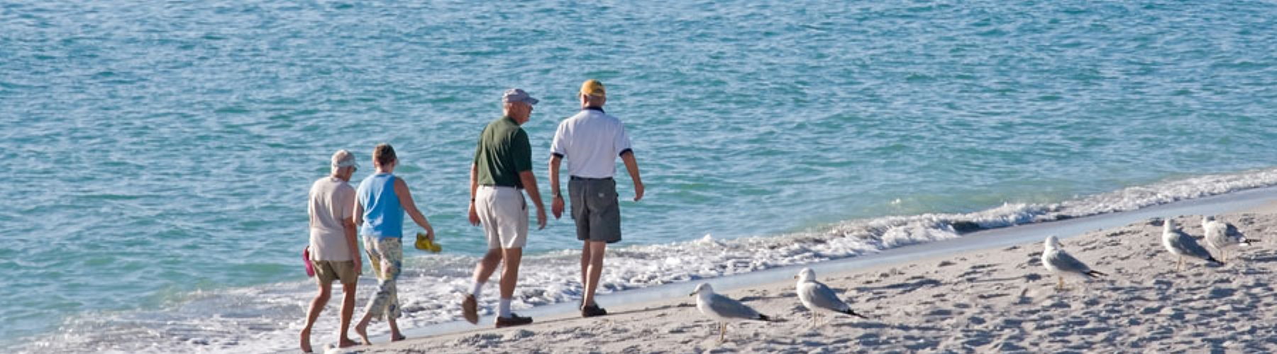 four people walking on a beach